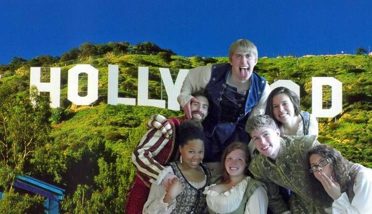 Group posing in Shakesperean clothing in front of a green screen Hollywood sign.